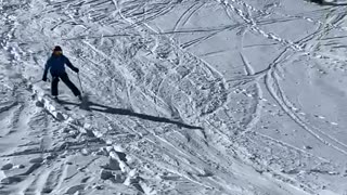 Skier skis down slope, flies off a ramp and falls