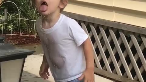 Little boy tries to drink sprinkler water trips on green house