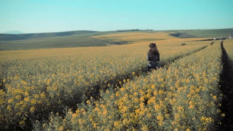 Back of a woman running in a field of flowers.