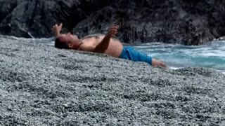 Man blue shorts throws sand on himself