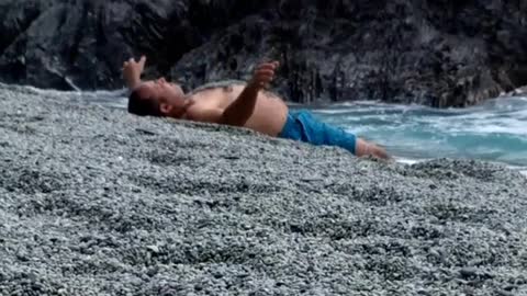 Man blue shorts throws sand on himself