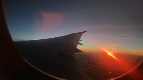 The sun rises outside the window on the plane.