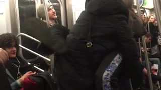 A couple hanging from subway rails man wraps legs on woman