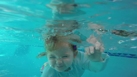 Skilled baby jumps in pool, floats on her own