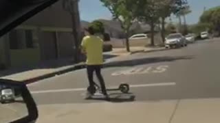 Kid yellow shirt using bird electric scooter while riding skateboard