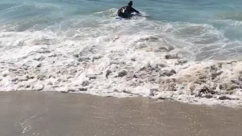 Guy in black wetsuit gets knocked down by wave