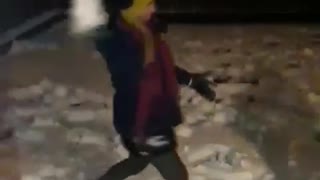 Girl fails to throw snowball then slips backwards in the dark