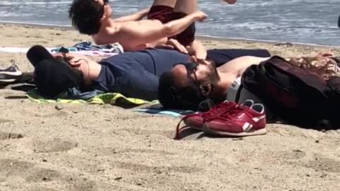 A guy laying on beach doing ab work out