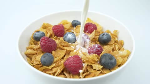 Pouring fresh milk over a bowl of cereal