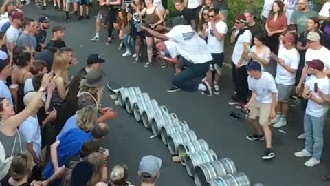 Guy skateboard jumps over beer kegs
