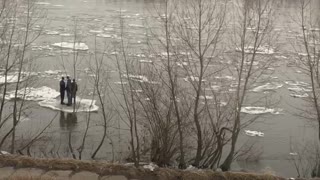 People Floating on Ice in a River