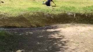 Man jumps over stream and slips