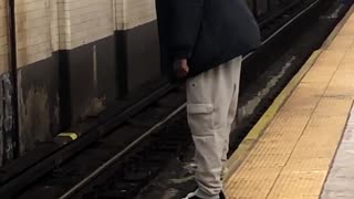 Man hangs his toes over the edge of subway train platform