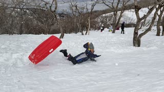Pt. 2 boy slides down snowy slope, flies off ramp and falls