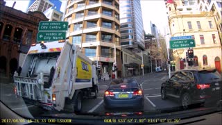 Pedestrians Walk in Front of Garbage Truck