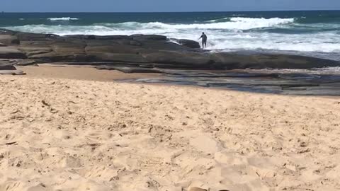 Guy fishing on rocks by ocean gets hit with wave and falls in
