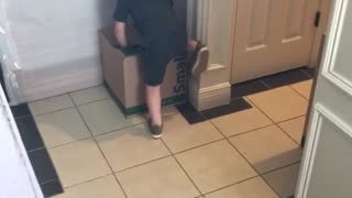 Little kid boy runs to box and tries to climb up gives up then hits head on cabinet door