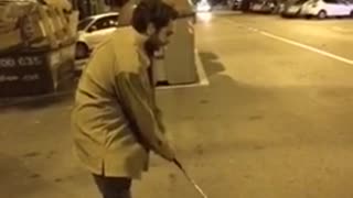 Man hits can with golf club on street at night