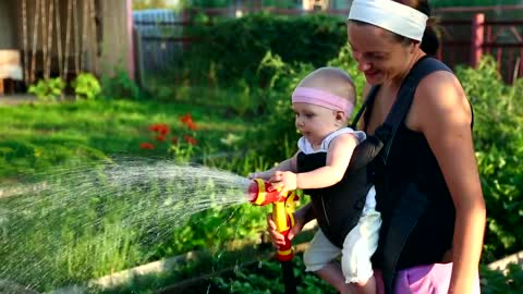 Mom watering the garden with her baby