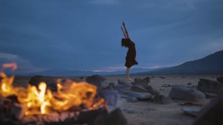 Deserted plain with a campfire and a woman practicing yoga