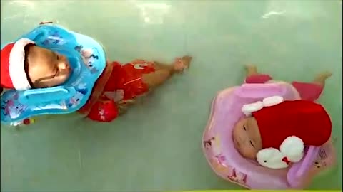 Twin babies swim adorably while wearing Santa outfits