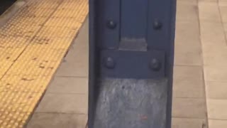 Man peeing behind a metal pillar at subway station