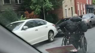 Music wheel chair guy trying to make his way down street past red sweater guy