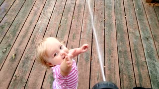 Toddler adorably entertained by water hose