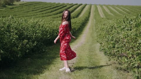 A Woman In Red Floral Dress Posing In A Plantation Field