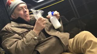 Man eats nuts out of bad and drinks milk on subway train