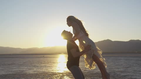 أزواج يرقصون على الشاطئ أثناء غروب الشمس