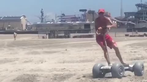 Guy red swim shorts riding skateboard sand beach scooter