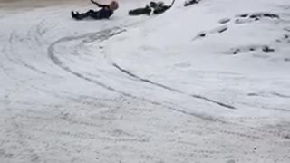 Boy on black motorcycle slips falls snow