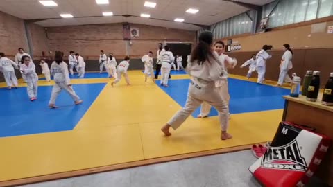 A boy and a girl wrestle in a Taekwondo gym