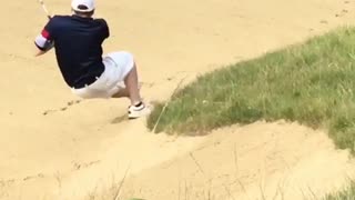 Guy playing golf falls as he swings