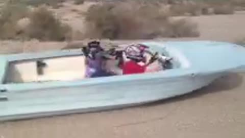 Trio Of Kids Ride In Boat Being Dragged Behind A Truck Down Dirt Road