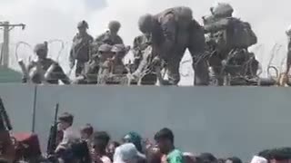 US soldiers pull a baby over a wall outside of the Kabul airport.