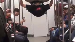 Guy hanging by feet in subway dancing upsides down hands