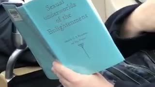 Guy intently reads book called "sexual underworld of the enlightenment" on subway train