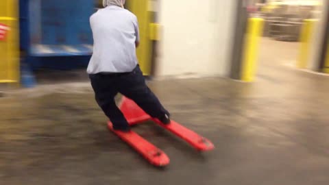 Worker Riding Pallet Jack Slides in Style on Reaching Destination