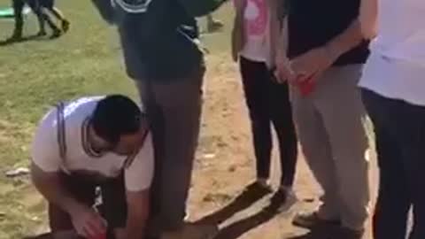 Guy pushed back onto friend kneeling on the ground and falls over