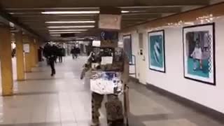 Cardboard box man walks around subway station with a cane