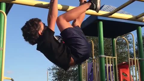 Kid in black run dmc shirt on yellow monkey bars falls down