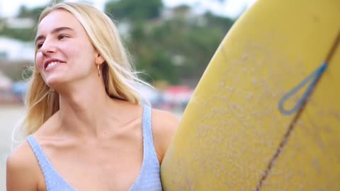 A BEAUTIFUL BIKINI WOMAN SMILING ON THE BEACH AND SURFING