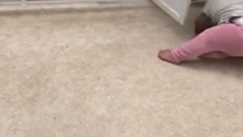 Baby in pink opens cabinet and falls