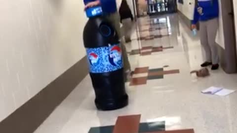 Teen jumps over huge blue soda bottle and falls in hallway