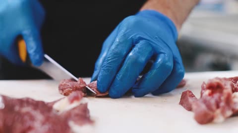 view-of-a-person-cutting-a-raw-meat-using-a-kitchen-knife