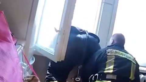 Fireman Catches A Falling Man with half his body outside a window