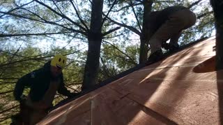 Placing panels on the roof of the 100% cedar treehouse by Bigfoot Treehouses