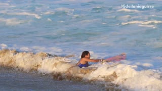 Girl pink surfboard blue bikini running out of water from wave gets knocked over